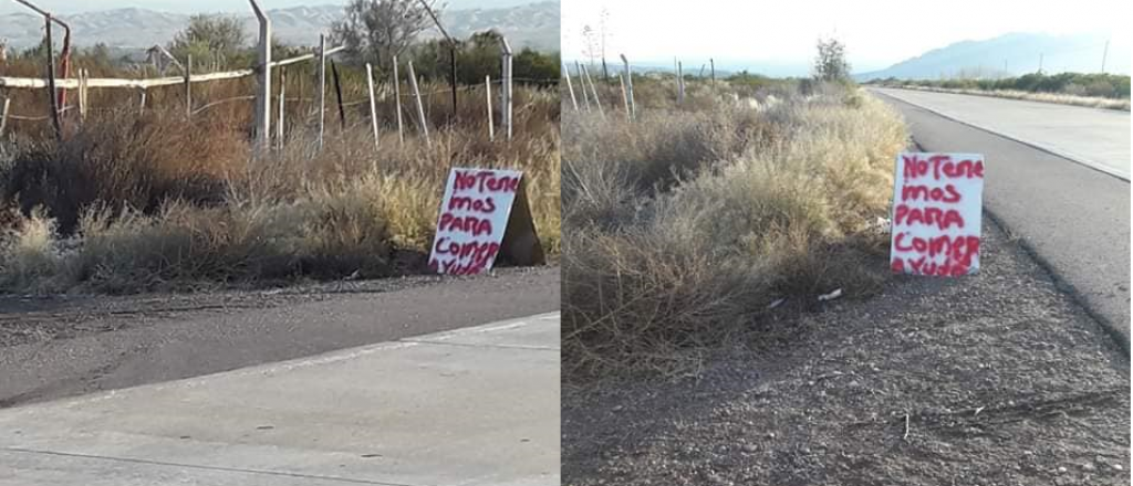 Dos personas piden comida con un cartel al costado de la ruta, en Luján