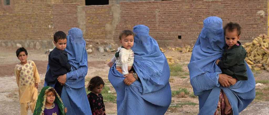 Mujeres cruzan a sus hijos por sobre el muro del aeropuerto de Kabul